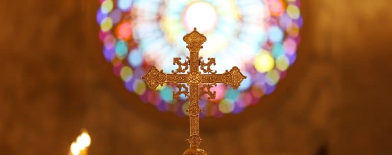 A cross on a church roof against a bright sky